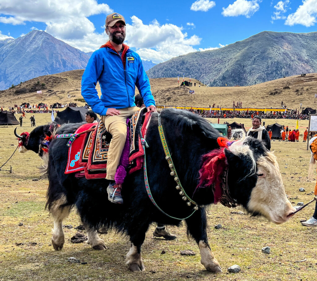 Chris riding on a yak.